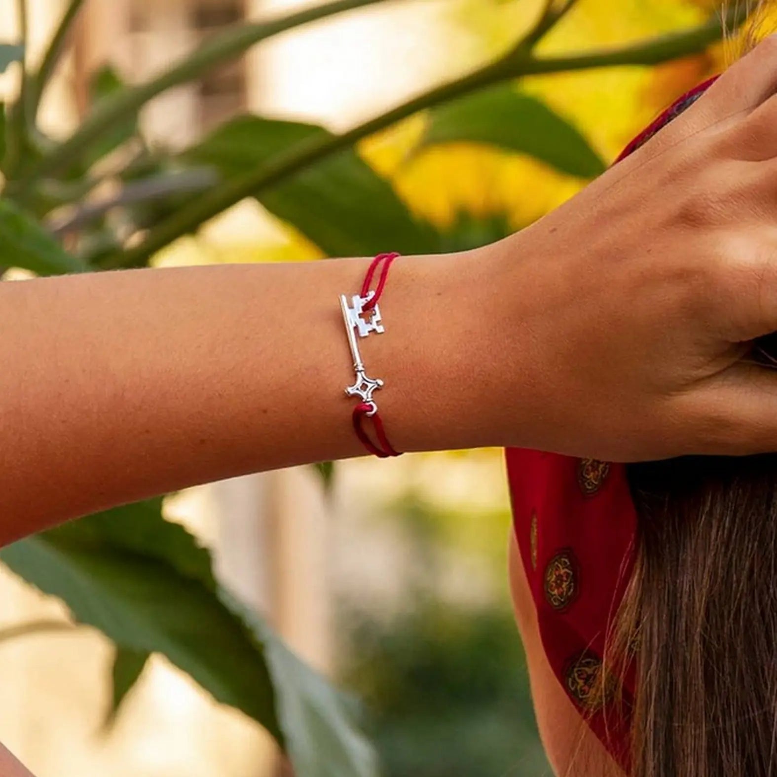 bracelet genevakey en argent rhodié et cordon rouge sur le poignet d'une femme