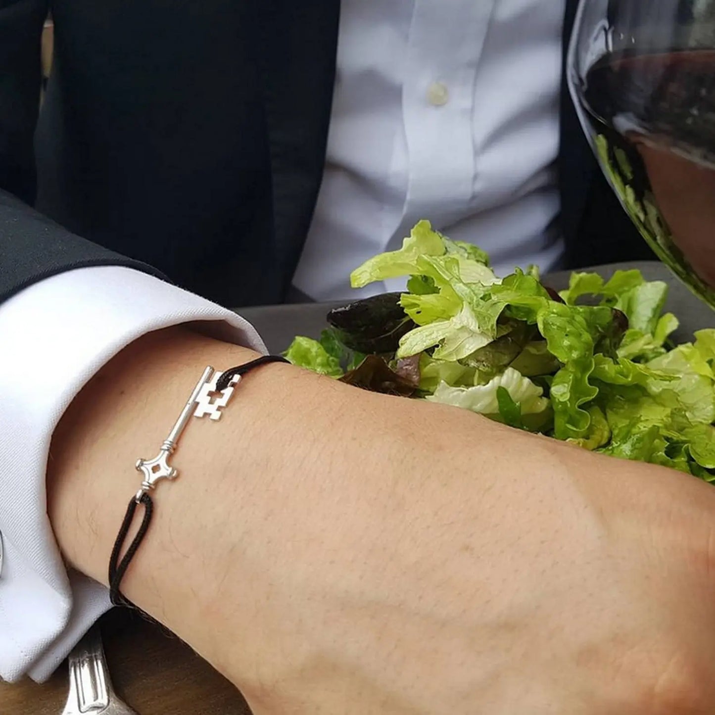 bracelet GenevaKey en argent rhodié et cordon noir sur le bracelet d'un homme qui mange