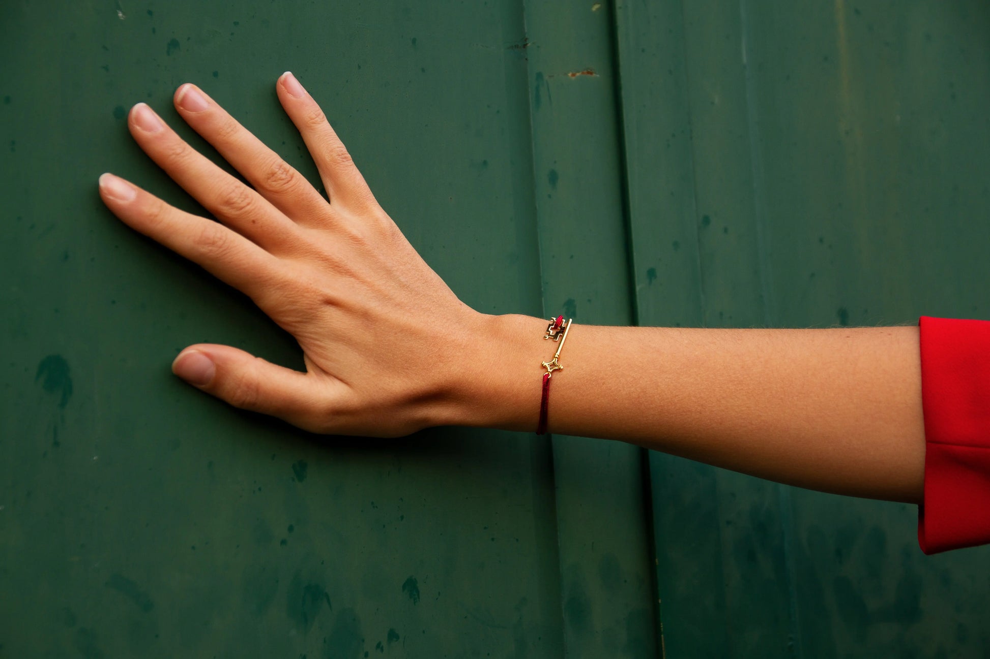 Bracelet GenevaKey en argent plaqué or jaune et cordon rouge sur le poignet d'une femme