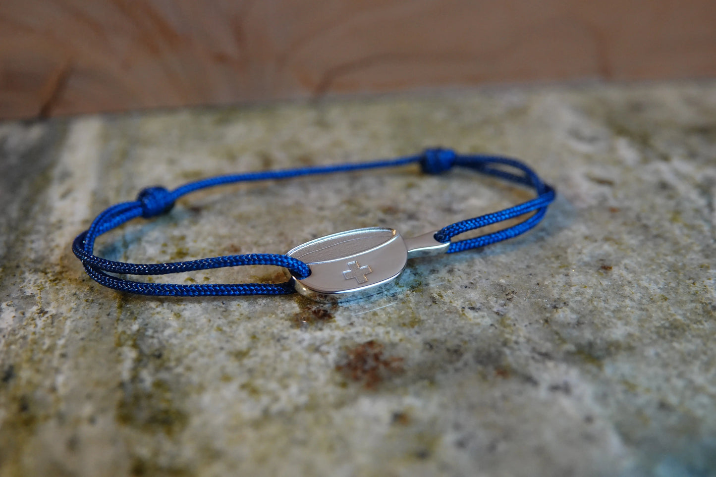 Bracelet SwissFondue en argent rhodié et cordon bleu posé sur une table en marbre