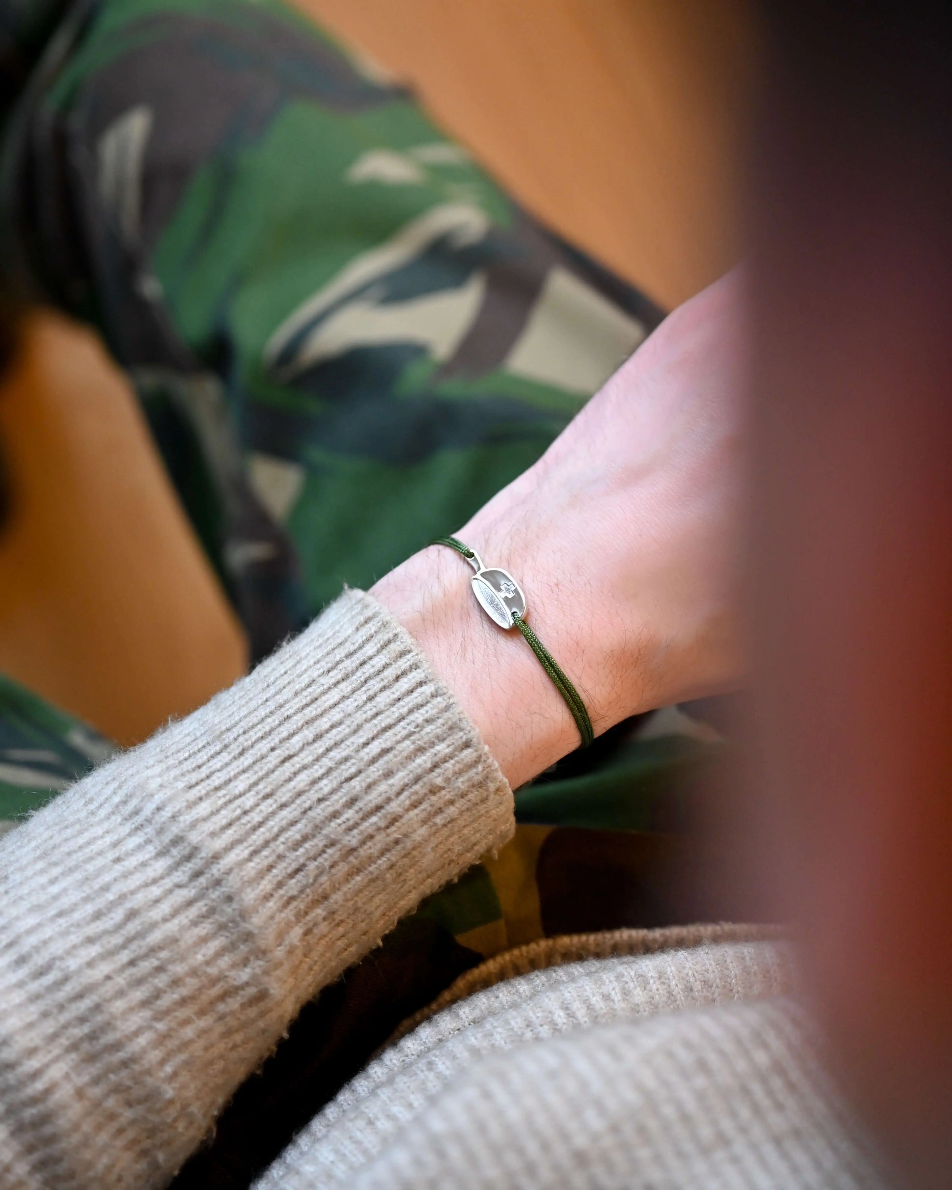 Bracelet SwissFlag en argent rhodié avec cordon vert sur un poignet d'homme
