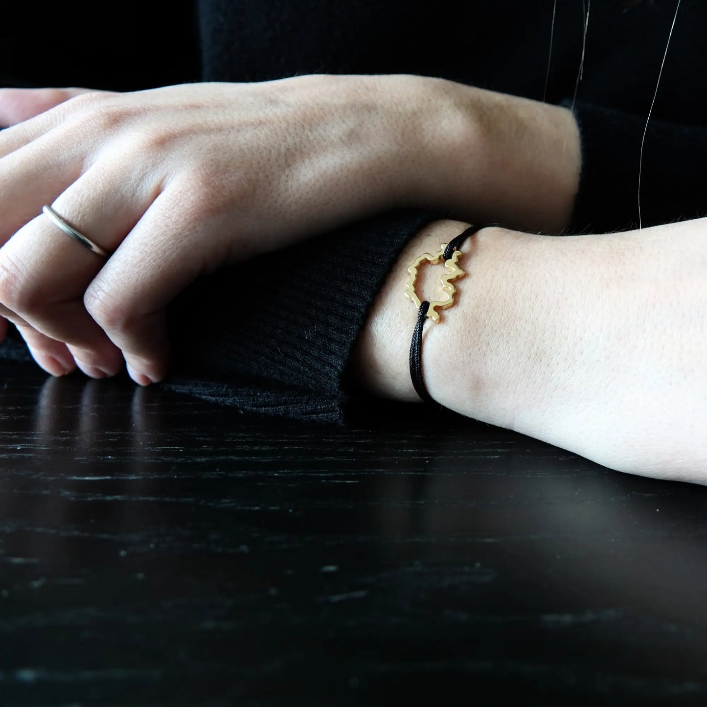 Bracelet SwissMap en argent plaqué or jaune et cordon noir sur un poignet de femme