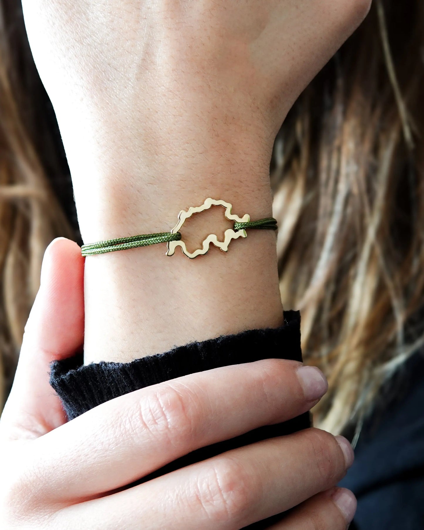 Bracelet SwissMap en argent plaqué or jaune et cordon vert sur un poignet de femme