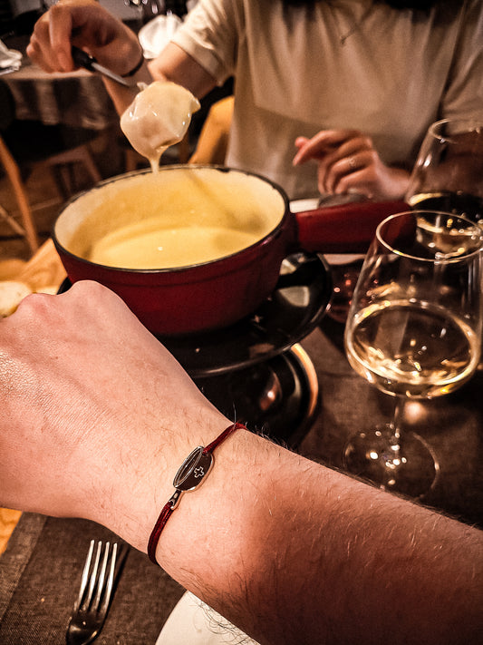 Bracelet SwissFondue devant un caquelon de fondue suisse