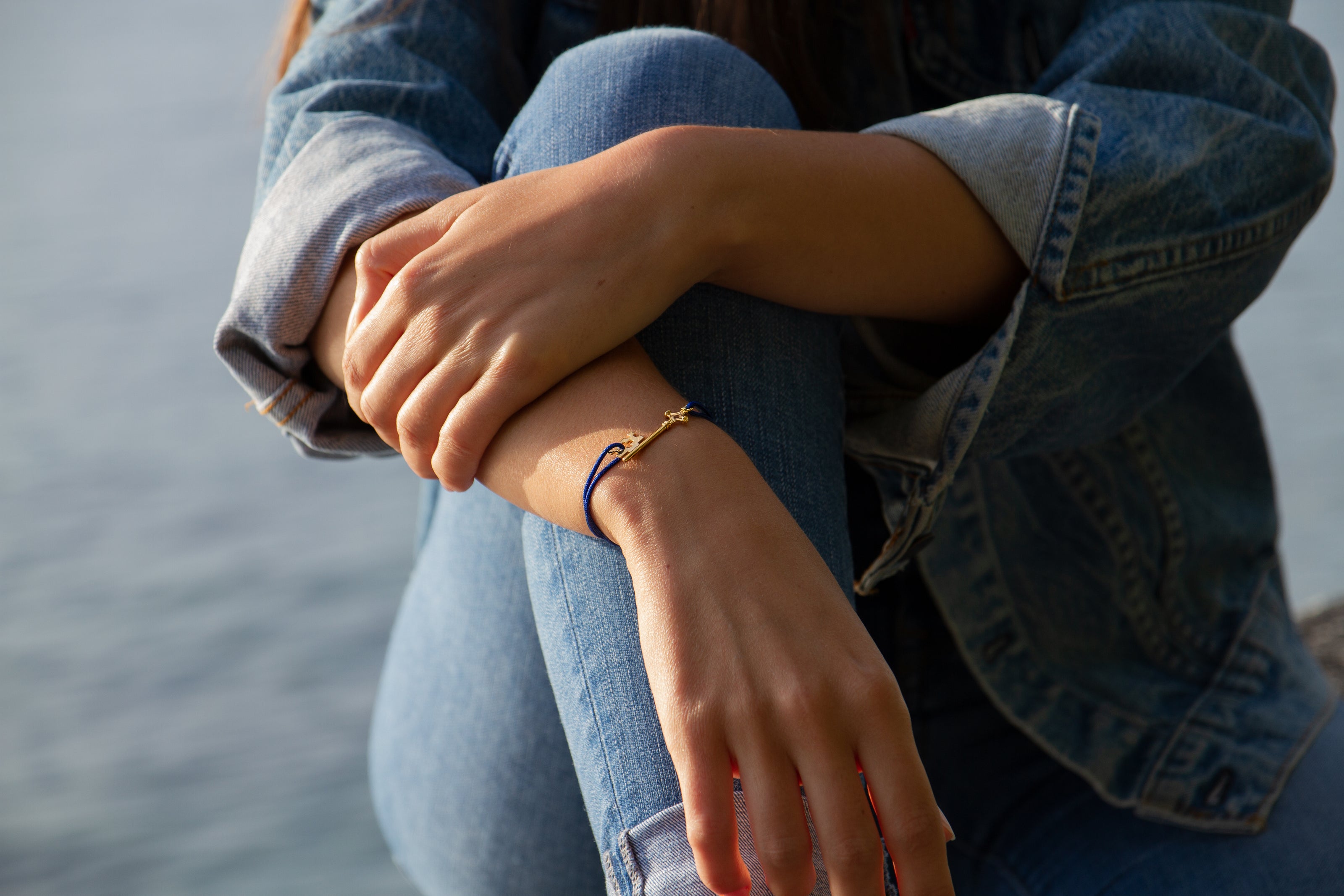 Bracelet GenevaKey en argent plaqué or jaune et cordon bleu sur le poignet d'une femme
