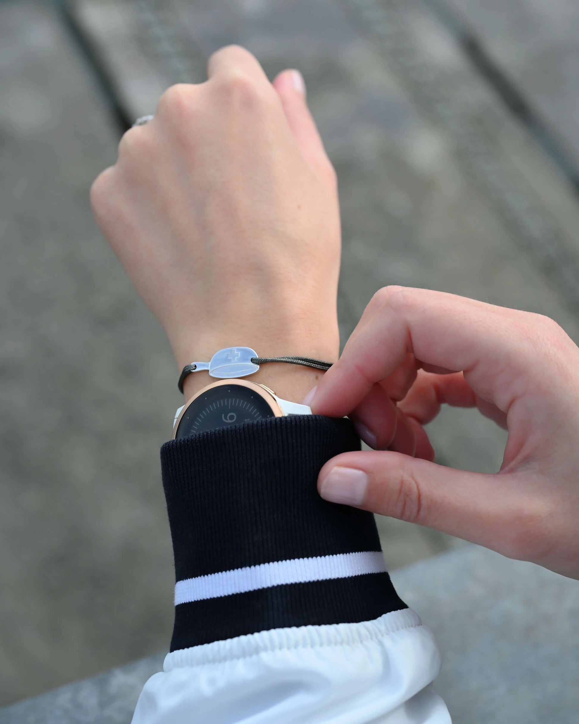 Bracelet SwissFondue en argent rhodié et cordon gris foncé sur le poignet d'une femme qui fait du sport